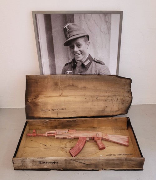 Жертва­-преступник, Kastenobjekt mit AK 47 (mit farbiger Fassung), 2025